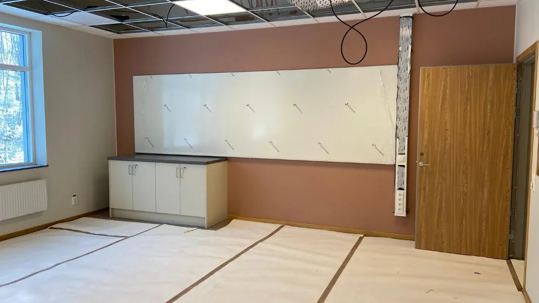 Klassrum för årskurs 4-6 på Högvadskolan, med en röd fondvädd och en vit whiteboard på väggen.