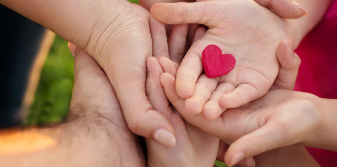 mor, far och barn händer som håller ett rött hjärta