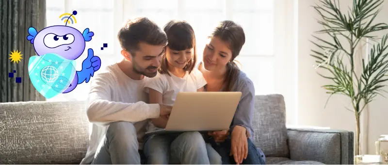 Två vuxna sitter tillsammans med ett barn och kollar på en dator.