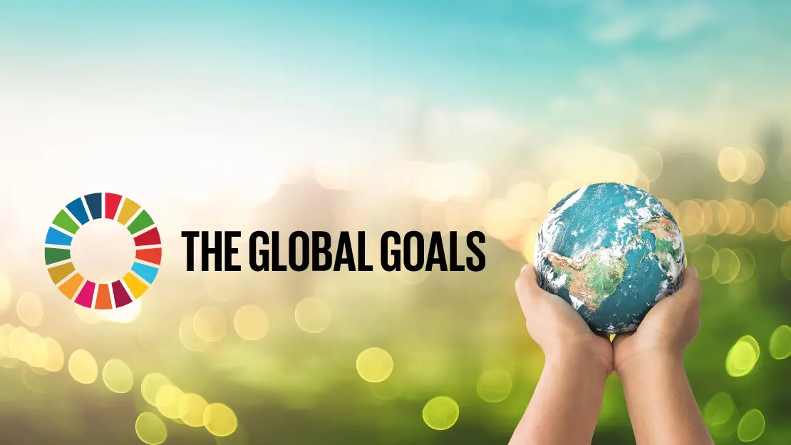 två händer håller upp en globus, loggan för globala målen finns bredvid