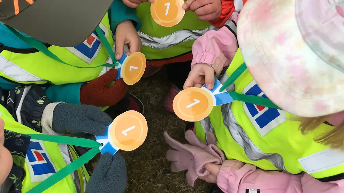 Barn står i en cirkel och tittar på sina guldmedaljer