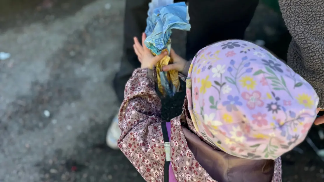 Ett barn med färggrann jacka håller i en pappers förpackning.