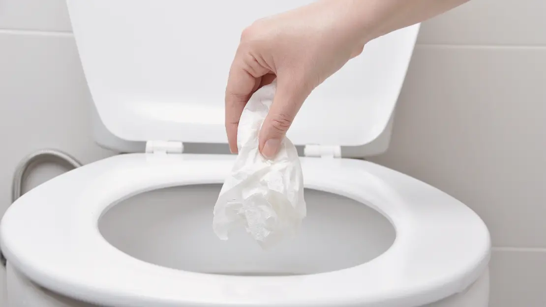 Hand slänger papper i toalett