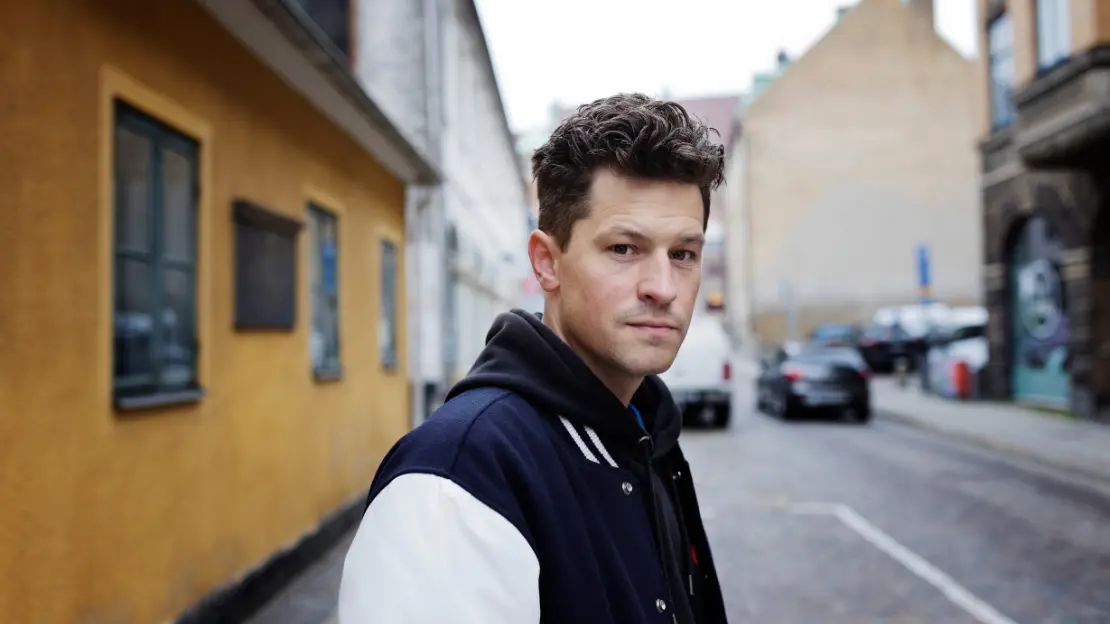 Henrik Wahlström står på en gata med byggnader. Han ser in i kameran. 