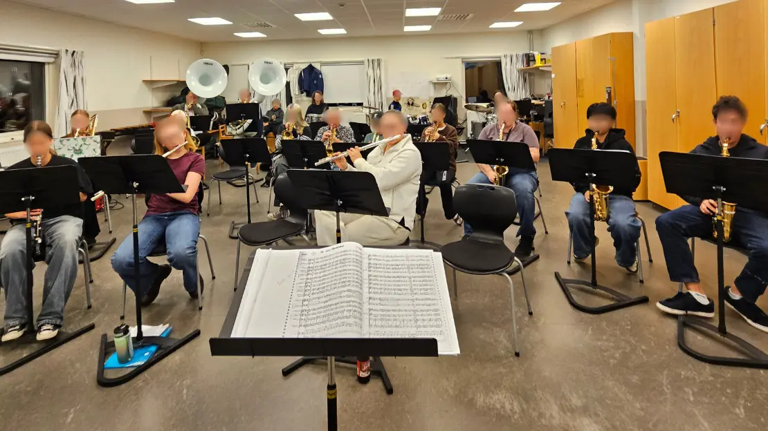 En grupp personer sitter med musikinstrument och noter framför sig.