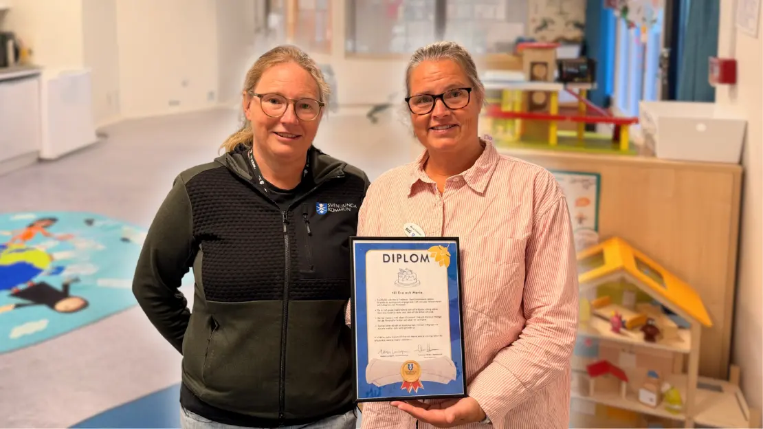 Eva och maria står med ett diplom i handen och ser glada ut.