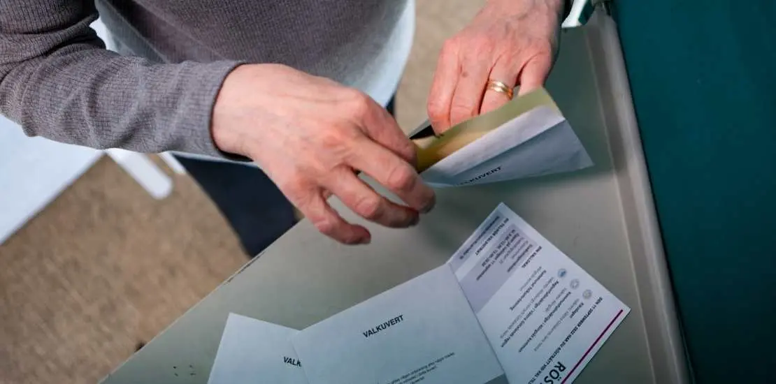 Person lägger sitt röstkort i ett kuvert.