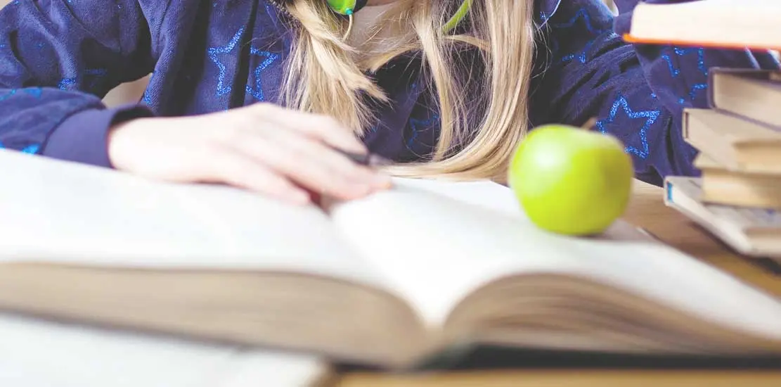 någon som sitter och läser en bok och äter äpple sedan lagt de på ena sidan av boken