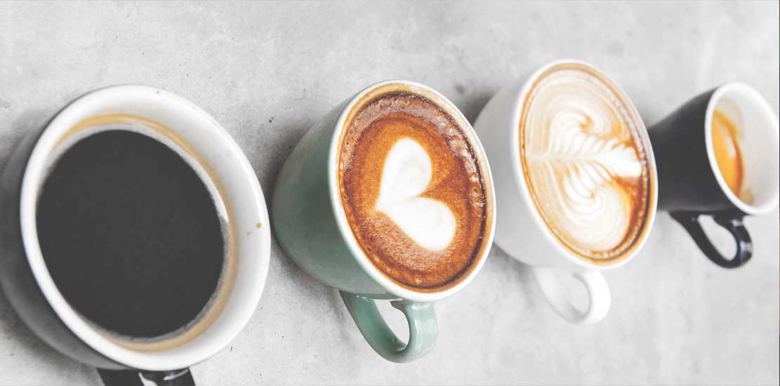 fyra olika kaffekoppar med olika mönster i skummet
