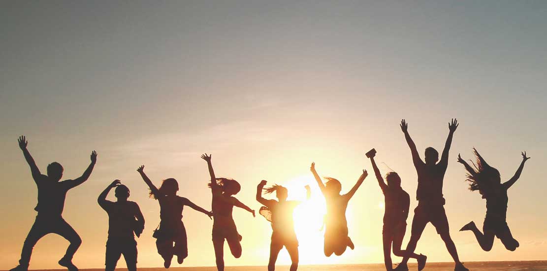 ungdomar hoppar tillsammans i solnedgången