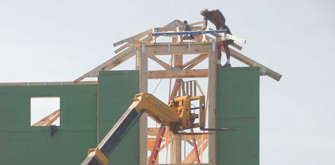 person arbetar på taket till ett bygge, huset är grönt