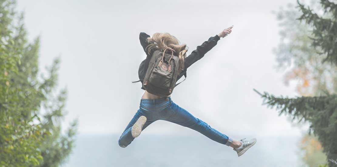 en tjej som har en väska på ryggen och hoppar