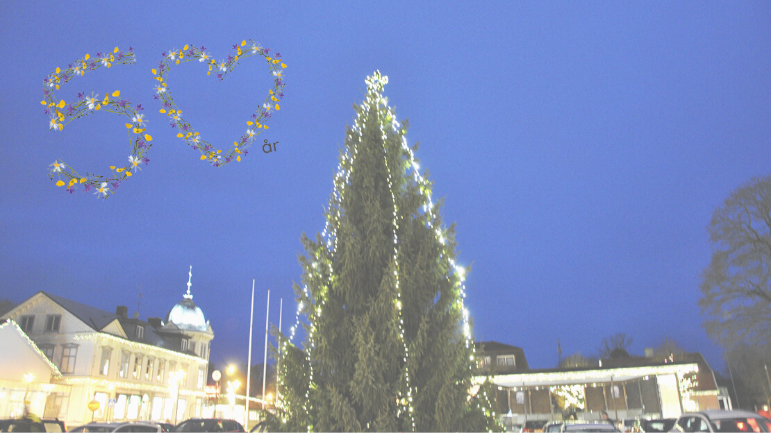 julgran på torget i Svenljunga tätort, ovanför svävar siffran 50 i blommor