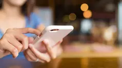 Två händer som håller i en rosa mobiltelefon och skriver i den.