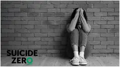 Person sitter på golvet med armarna framför ansiktet. I hörnet finns loggan för Suicide Zero.