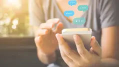 En person sitter och håller i en mobiltelefon och så är det pratbubblor ovanför