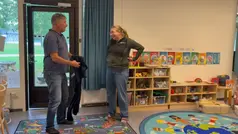 Två personer står och pratar i ett rum fullt med olika leksaker.