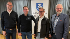 Fyra män står framför kommunloggan.