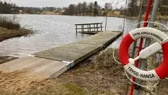 Badbrygga vid sjö, i förgrunden syns räddningsring.