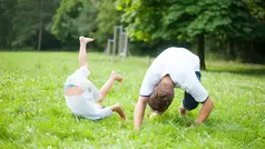 En pojke och en vuxen man som gör en kullerbytta.