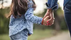 En flicka som håller en vuxes hand.