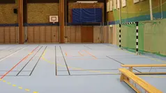 Idrottshall där man ser ett fotbollsmål och basketkorg. 