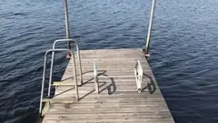 en brygga vid vatten. Till vänster är det en badstege.
