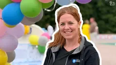 Elinore  ler och är glad framför färgranna ballonger.