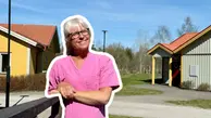 Helena är glad och ler framför två husbyggnader. 