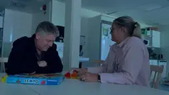 Två personer sitter i mörkret och spelar spel.