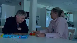 Två personer sitter i mörkret och spelar spel.