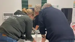 Två personer står och tvättar händerna i ett handfat.