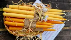 Fint gula och orangea omslagna stöpna ljus ligger i en korg. 