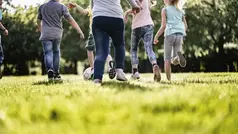 Barn springer på en grön äng.