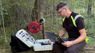 Christoffer Österling sitter på en stubbe med en laptop i kbät och en verktygslåda han kollar av värden på.