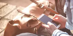 en elev som sitter och har sin väska i knät som stöd till mobilen
