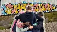 Ebba får en kram av några barn framför grafittimålningen på sommarzonen.