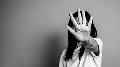 svart vit bild på kvinna som håller upp en hand framför ansiktet i en stopp-gest
