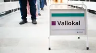 En skylt med texten "Vallokal" i ett stativ. Personer syns gående i bakgrunden.