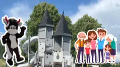 En lekplats med ett slott och en rutschkana. Maskoten Tjuris och en grupp personer står bredvid lekplatsen.