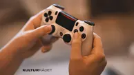 Två händer som håller i en vit spelkonsol.