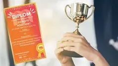 två händer lyfter upp en pokal, bredvid finns ett diplom